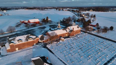 large christian church with steeple and cemetery graveyard covered in winter snow during golden hour light