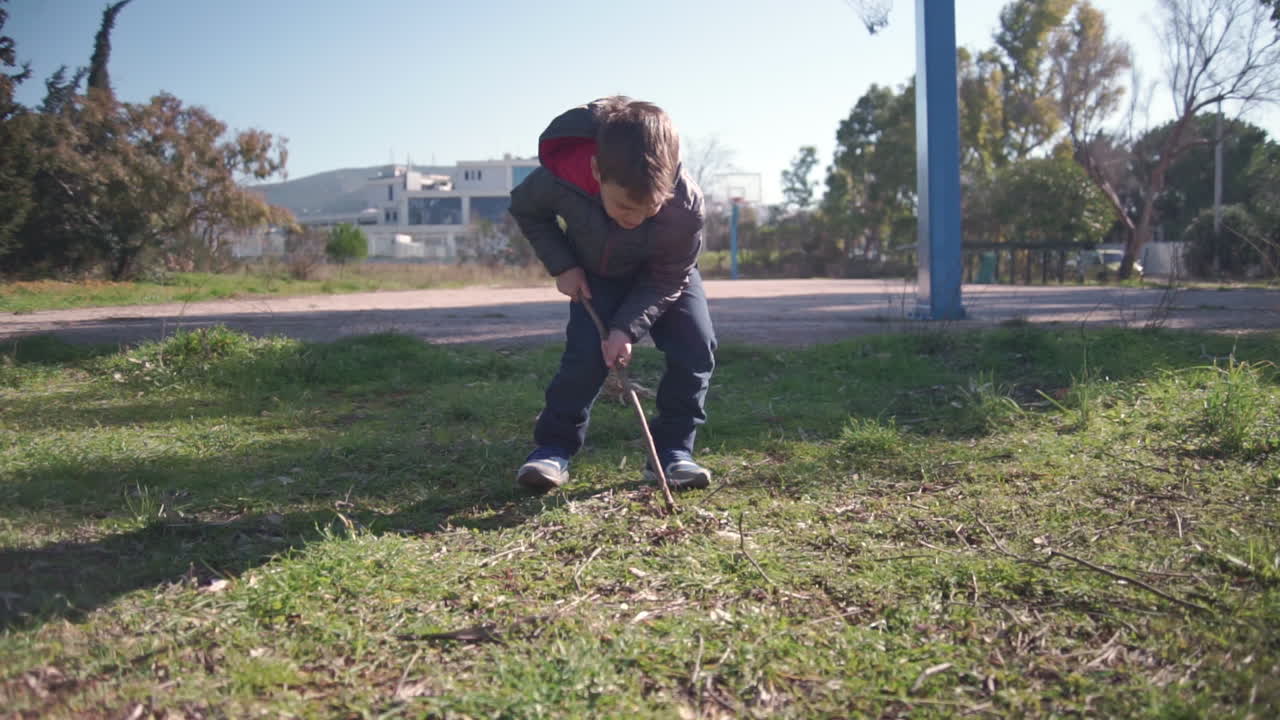 Wide shot of toddler in the fields digging with a wooden stick 60fps