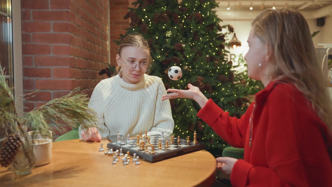 Ragazze che giocano a scacchi e fanno rimbalzare un piccolo pallone da calcio in un caffè