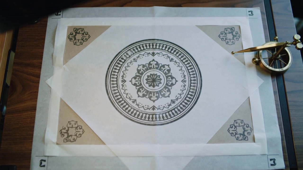 Camera panning up, sleeve entering top as medallion sheet staying centered by brass compass on desk