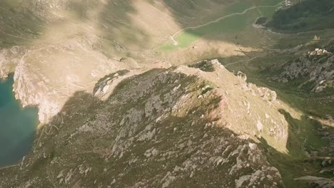 Exhilarating-and-captivating-aerial-footage-of-an-FPV-drone-descending-towards-Kleiner-Seefeldsee,-tracing-the-mesmerizing-path-of-a-stunning-waterfall-cascading-from-the-mountain-lake