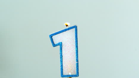 one birthday candle flickering and extinguishing on blue background