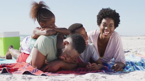 Video-of-happy-african-american-family-lying-on-beach-and-laughing