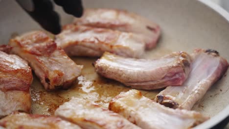 persona del cultivo cocinando costillas en la sartén