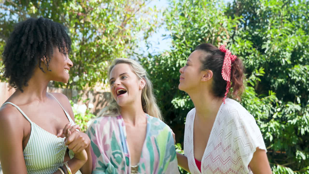 Diverse female friends enjoying sunny day by pool, smiling and embracing each other