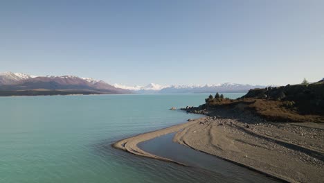 vistas al lago turquesa y a las montañas desde la playa rocosa