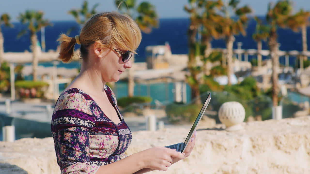un turista con gafas de sol disfruta de la tableta en el fondo de un paisaje tropical