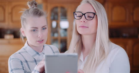 female coworkers discussing over digital tablet in office 1