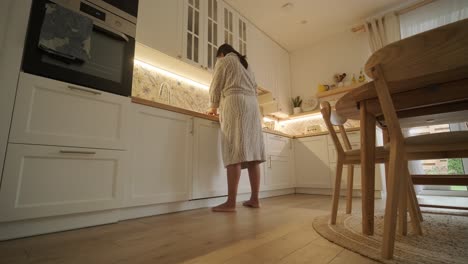 a pregnant woman enjoying her daily routine at home, relaxing in the living room and eating in the kitchen. the scene highlights comfort, maternity, and moments of self-care in a cozy setting