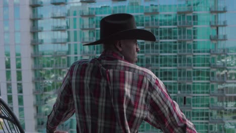 black man with black cowboy hat looking over balcony