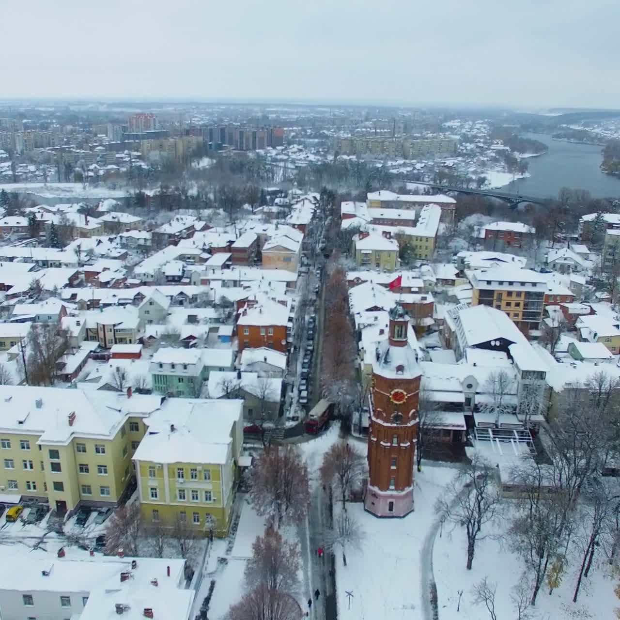 Urban landscape on winter daytime. River floating through the city at backdrop. City in snow. Top view