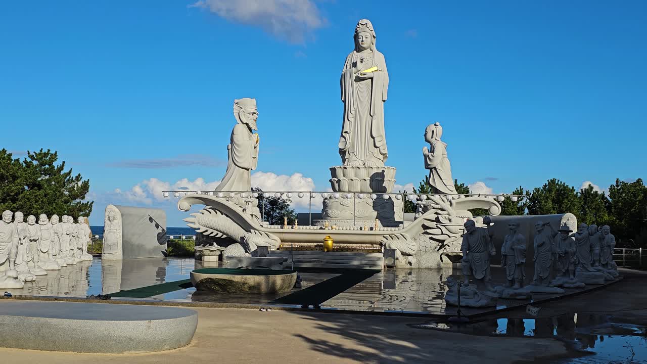 Zoom in to Avalokiteshvara or Hyuhyuam Sea Guanyin Statue at Hyuhyuam Hermitage Buddhist temple in South Korea, devout figurines worship and learn at peaceful altar