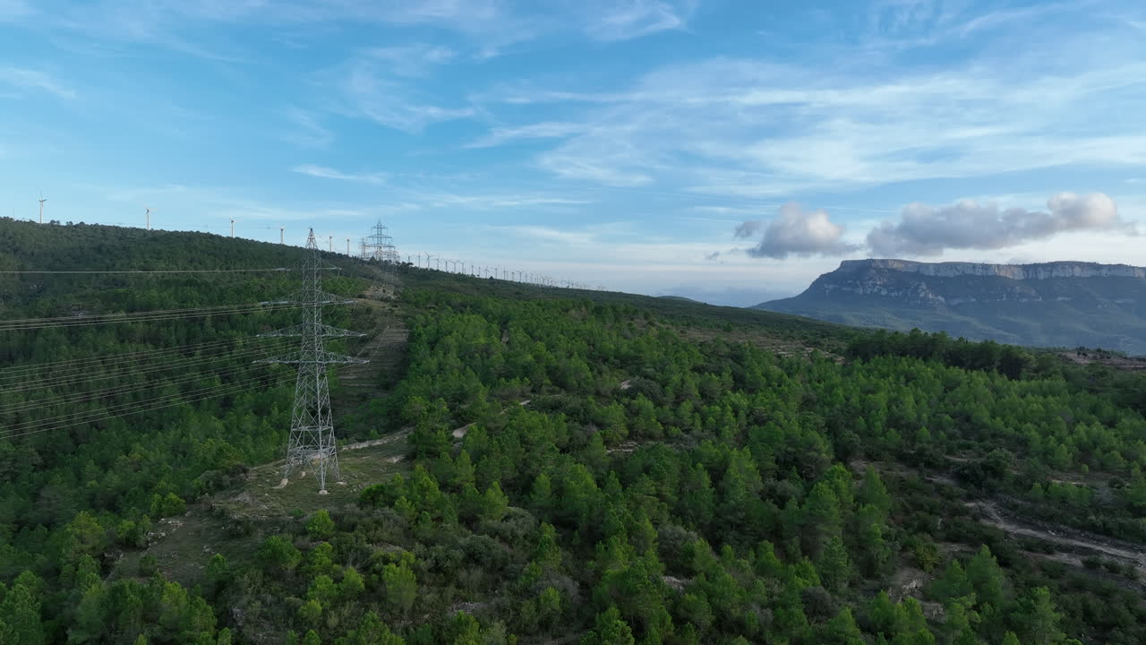 High voltage electric pylons with wind eolic farm in background, Trucafort, Pradell de La Teixeta, Tarragona in Spain
