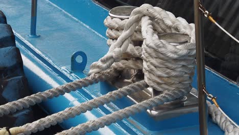 close-up of mooring ropes tied to cleats on a blue boat