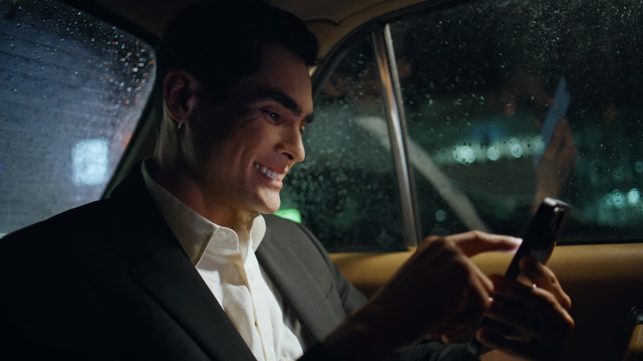 jefe emocionado regocijándose teléfono celular noche coche primer plano. hombre de negocios feliz gestando