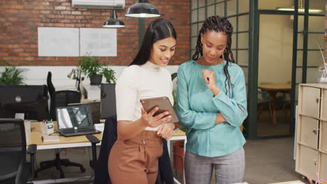 Happy-diverse-female-architects-looking-at-architectural-models-and-using-tablet-at-office