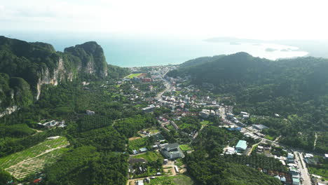Aerial-view-shot-Ao-Nang-City-with-mountains-and-Tourist-Harbor-at-ocean-during-sunny-day---Wide-shot-of-thailand-coastline-in-summer