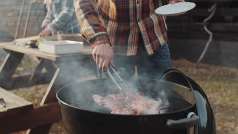 hombre cocinando carne en la barbacoa en el patio trasero