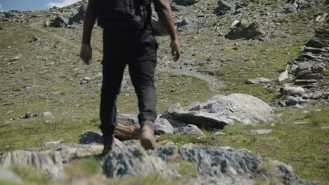 black male traveler with backpack walking across screen to explore the matterhorn mountainside in switzerland