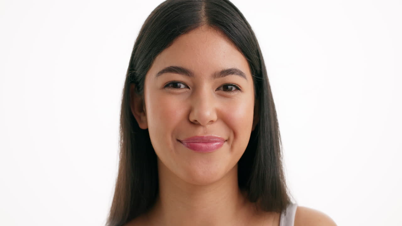 Portrait of a smiling woman making a mini heart gesture