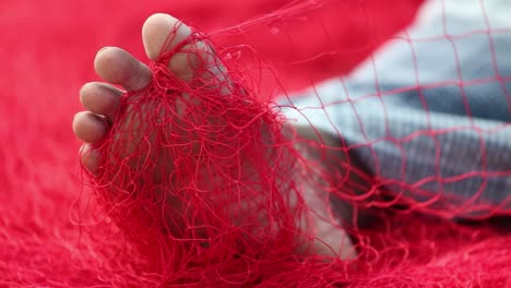 a red fishing net entangled in the right foot of a man who is continuously trying to set himself free