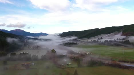 aerial shot moving towards mountains over misty valley floor