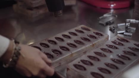 chocolatier at work drying chocolate poured in candy moulds