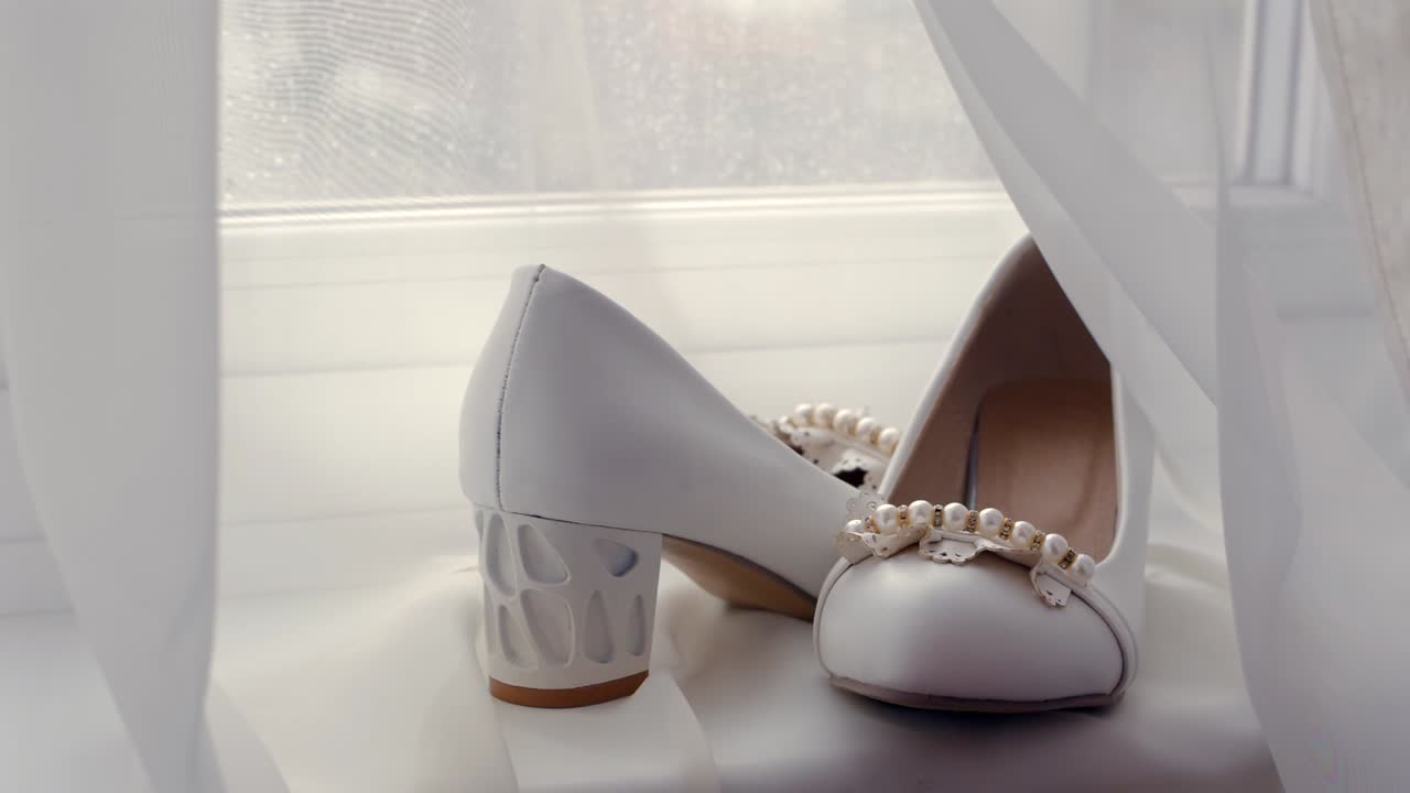 진주로 장식된 색 신부 신발의 드, 창문 근처에서 부드럽게 밝습니다.
