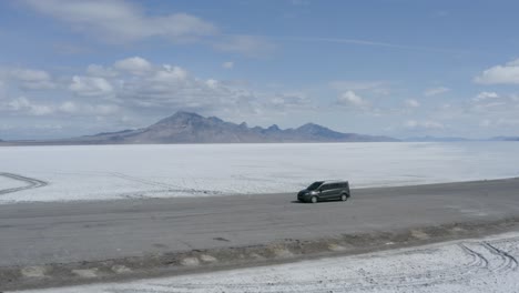 Coche-En-Carretera-En-El-Paisaje-épico-De-Las-Salinas-De-Utah-Bonneville,-Antena