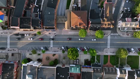 traffic jam on main street of small american town in ephrata. aerial top down rising shot. green trees in spring. roof top of row houses at sunset. pennsylvania in united stares.
