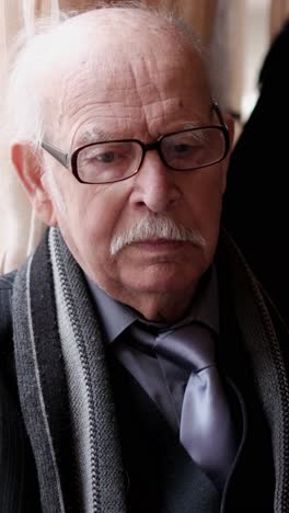 sad elderly man sits in armchair and takes container with pills. sad elderly man sits in armchair and takes container with pills. pensioner with grey beard takes small pill bottle and examines instruction with weary face
