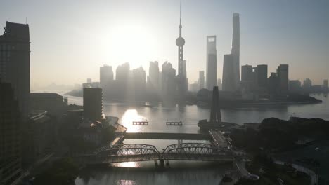 Early-morning-light-beaming-down-on-The-Bund,-Shanghai,-China-on-a-cold-winter-morning,-aerial