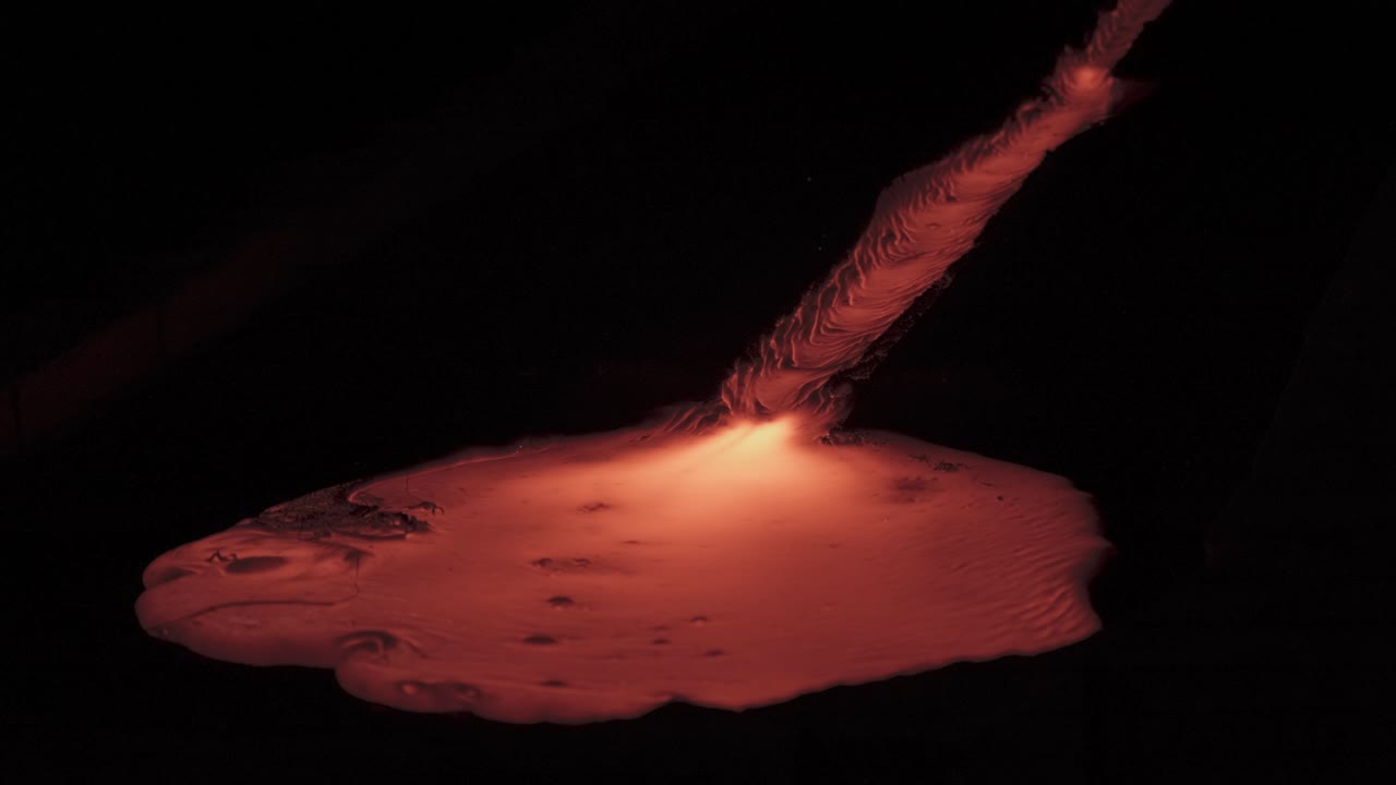 Magma lava flowing down stream, forming lava lake, cooling down turning from hot yellow to red