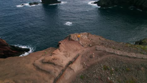 a person walking towards coastline hills, portugal, aerial drone, madeira