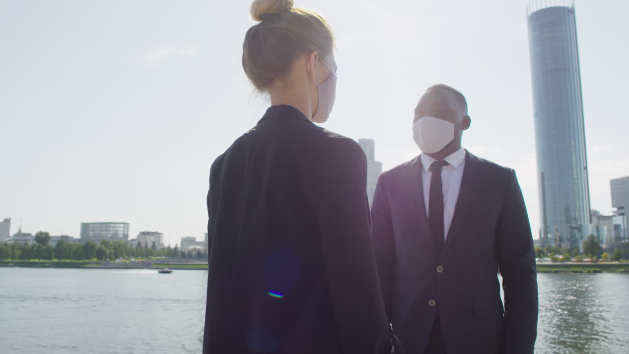 Business Couple In Masks Talking Near River