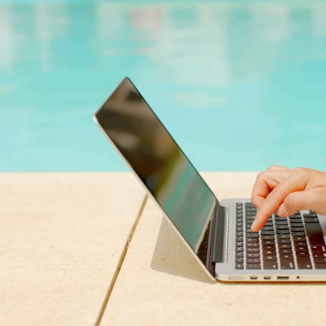trabajando en una laptop en el área de la piscina
