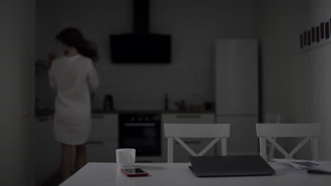 young woman coming into kitchen in morning. pretty lady making tea at home.