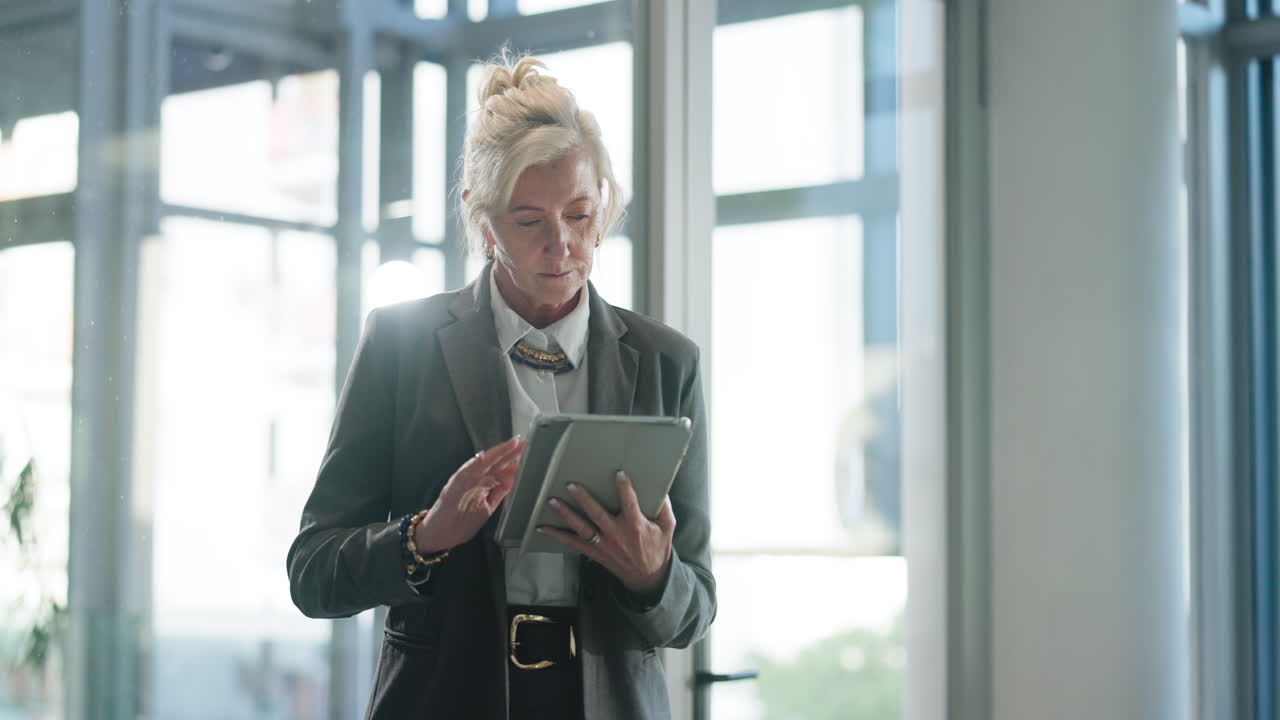 Moden forretningskvinde, der bruger en digital tablet på et moderne kontor.
