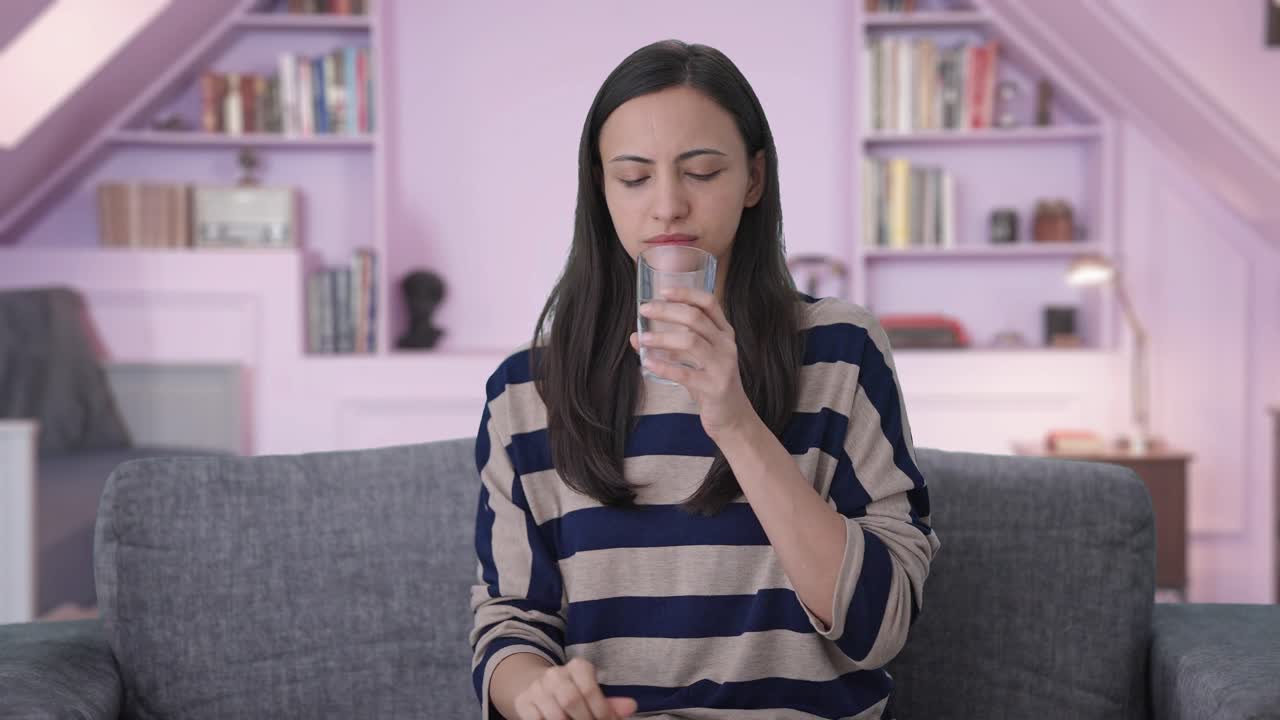 una chica india triste tomando su medicina.