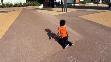 Joyful-3-year-old-black-child-enjoys-climbing-and-sliding-in-a-ramp-in-a-playground