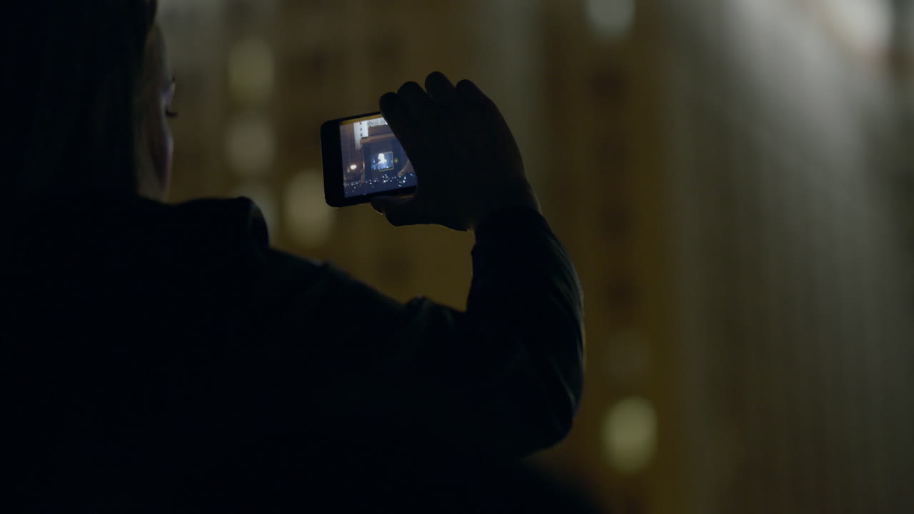 una mujer espectadora hace una serie de fotos del escenario a través de un teléfono inteligente en un concierto de música al aire libre