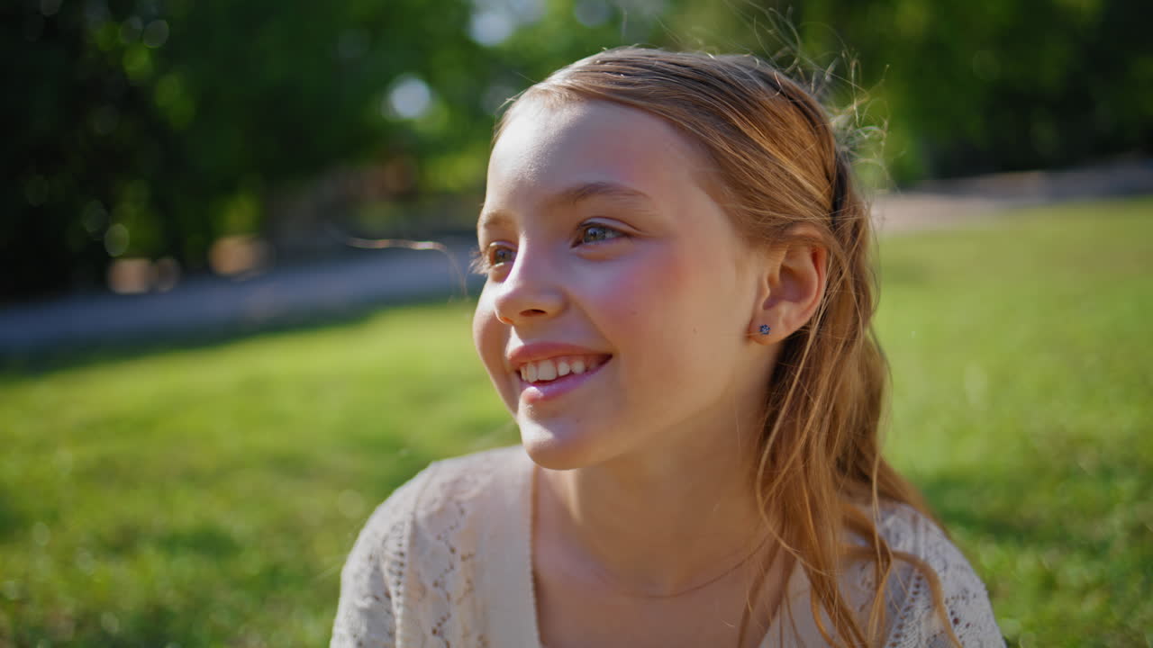 Smiling kid resting summer sitting at grass closeup. Child relaxing on sunshine