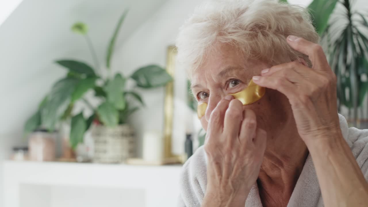 Senior caucasian woman applying medical eye patch in the bathroom
