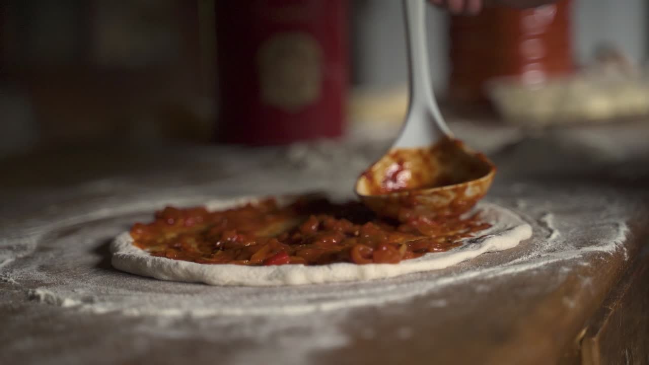 Salsa di pomodoro su pizza cruda fatta in casa con farina su tavolo di legno, Movimento lento.