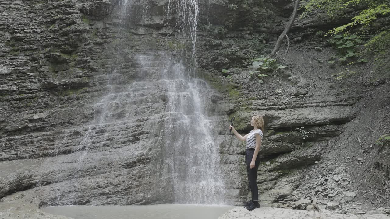 폭포 앞에서 셀피를 찍는 여자