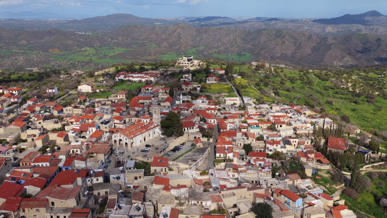 Veduta aerea con drone di un tradizionale villaggio cipriota che presenta una chiesa storica con campanile e tetti di tegole rosse. Pano Lefkara, Cipro.