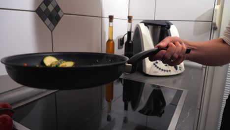 chef en la cocina arrojando verduras picadas en una sartén