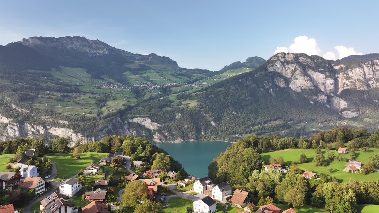 vista aérea sobre el área residencial de fizbach, revelando gradualmente el impresionante lago walensee en glarus nord, suiza