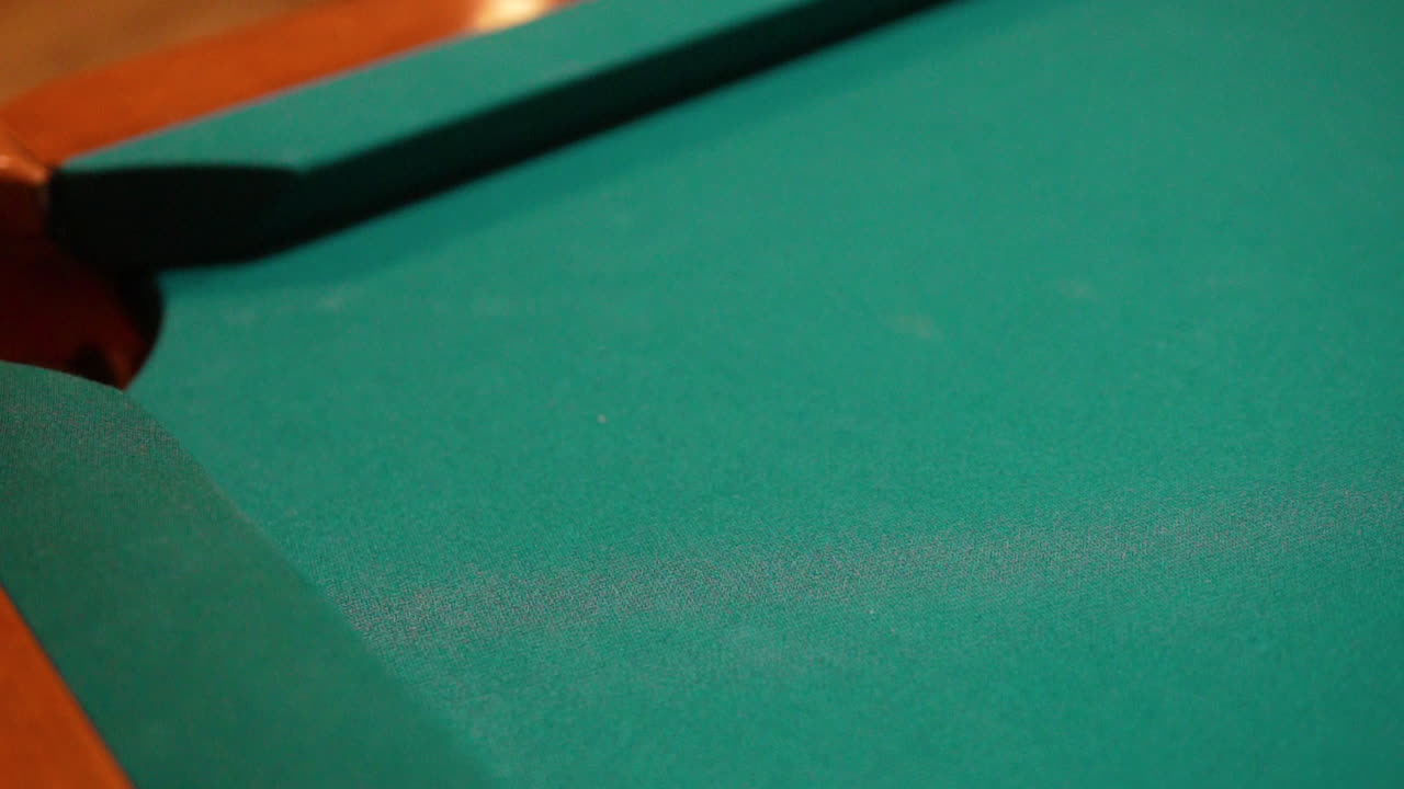 Slow Motion Billiards solid black 8 ball shot in corner pocket on pool table with green felt and brown pockets using the cue ball and back spin or draw Close Up with Red Spinning Dots