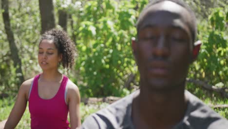 diverse couple practicing yoga and meditating in countryside